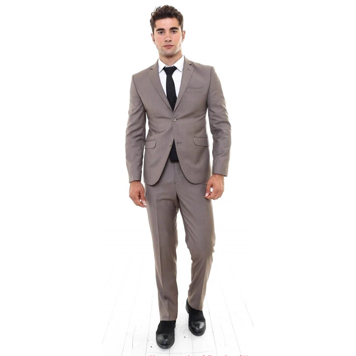 En mand i lysebrunt jakkesæt, hvid skjorte, sort slips og sorte sko står med front mod en hvid baggrund.